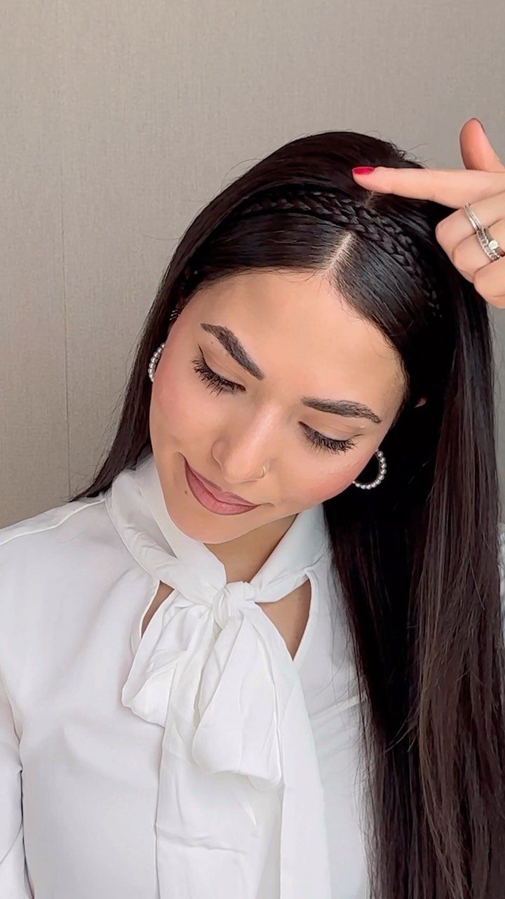 Woman with long dark hair featuring a braided headband hairstyle and white blouse.