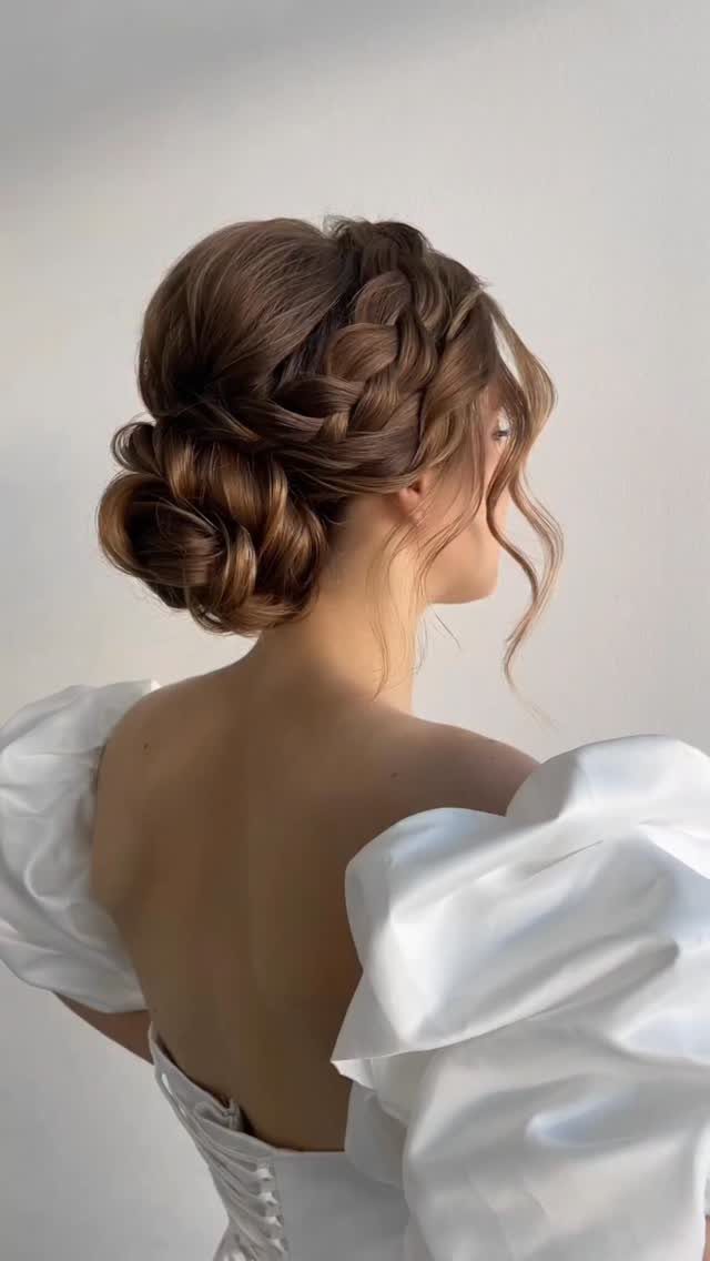 Woman with brown hair in an intricate braided updo wearing a white dress.
