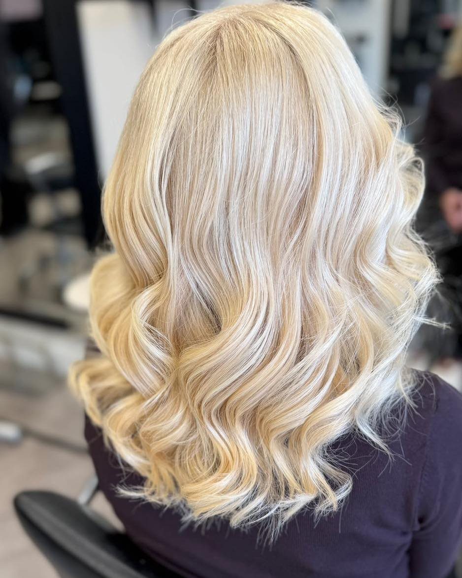 Blonde shoulder-length hair styled in a voluminous, polished classic blowout with soft waves.