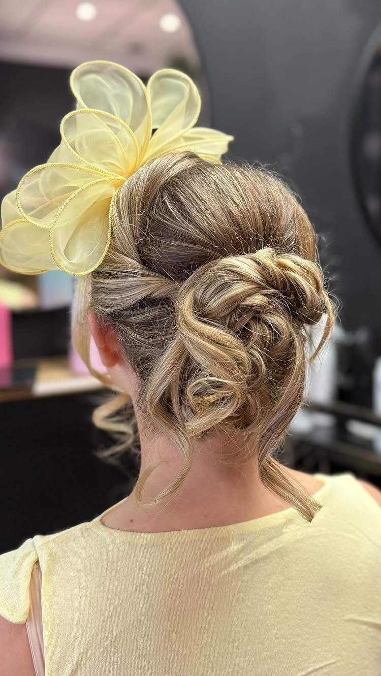 Blonde hair in a low textured updo with a large yellow flower accessory