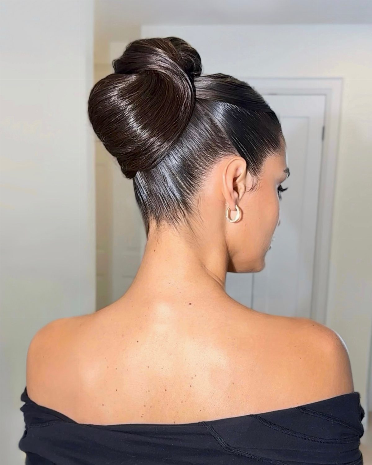 Woman with dark hair styled in a sleek high ballerina bun updo