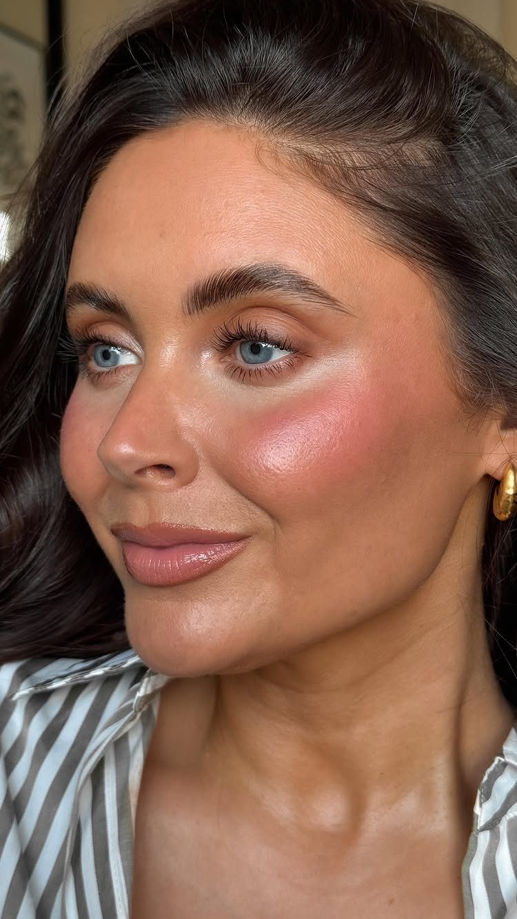 Woman with blue eyes wearing natural wedding makeup and gold hoop earrings.