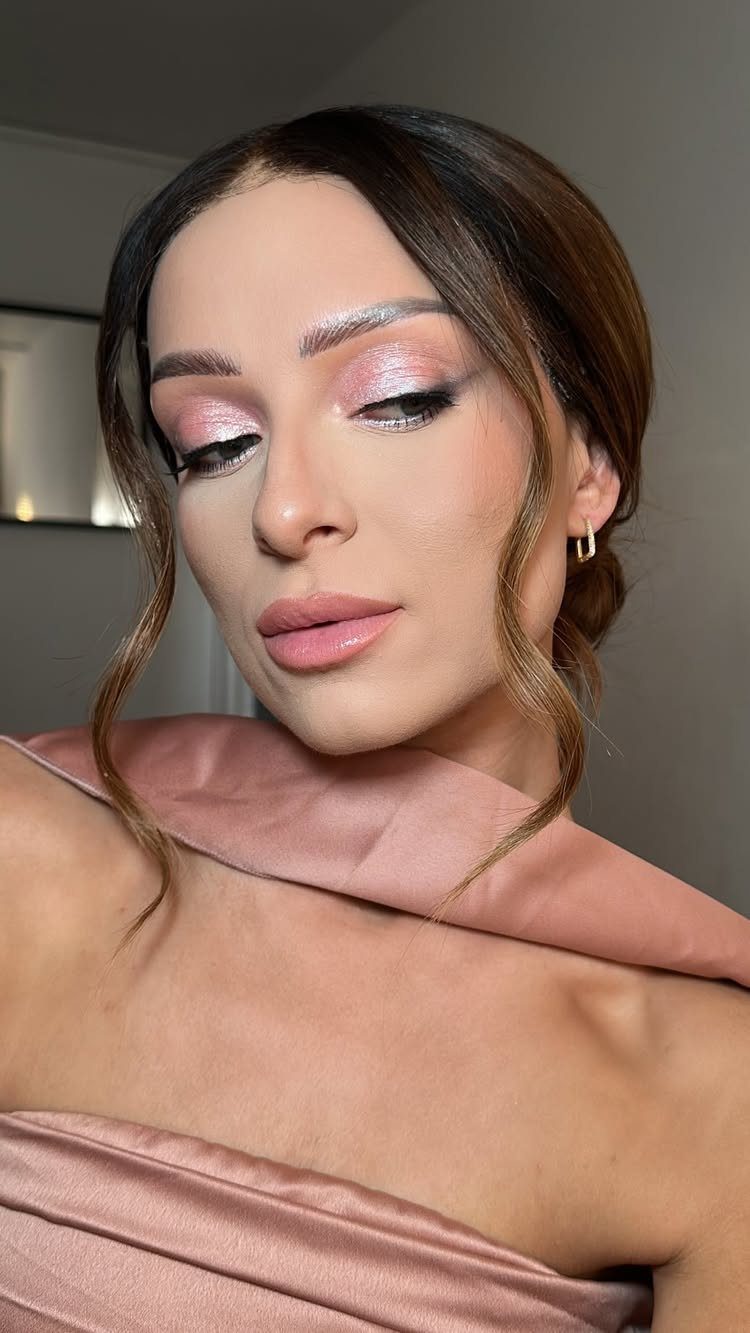 Woman with groomed, brushed eyebrows and shimmery pink makeup wearing a pink satin dress.