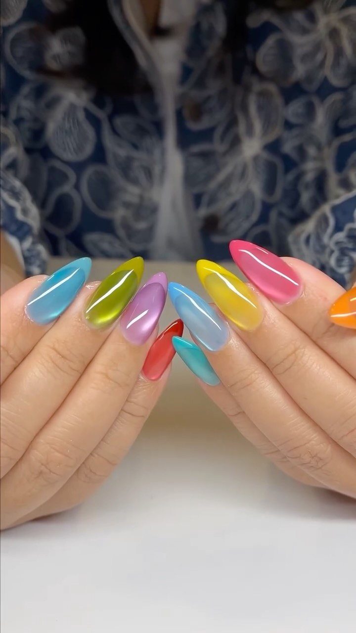 Colorful translucent jelly nails in various bright shades on almond-shaped fingertips.