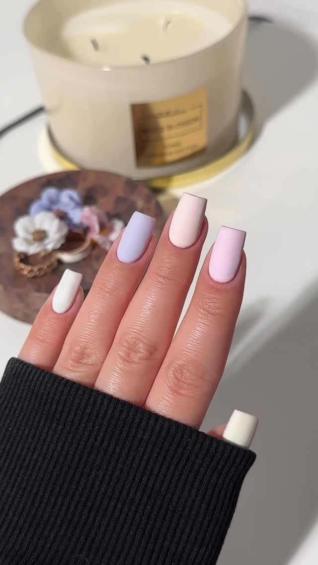 Matte pastel nails in lilac, peach, pink, and white on a hand.