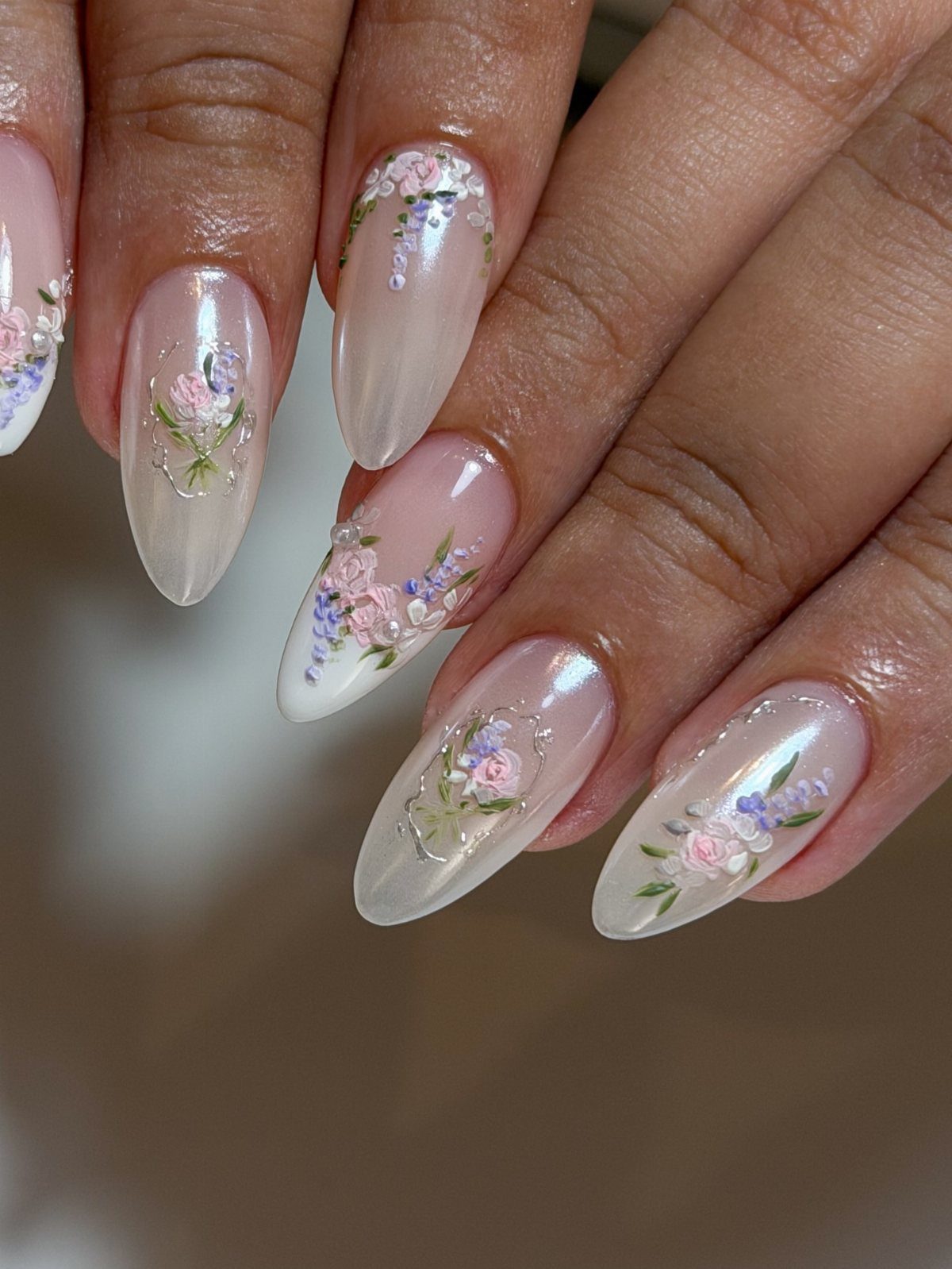 Almond-shaped milky white nails decorated with tiny pink and purple pressed flowers.