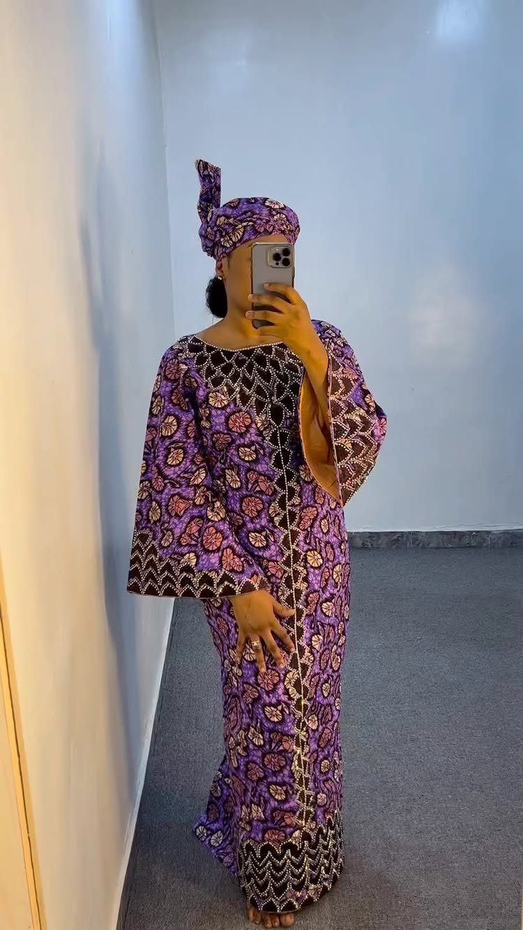 Woman wearing a purple patterned Ankara wedding guest dress and matching gele head tie.