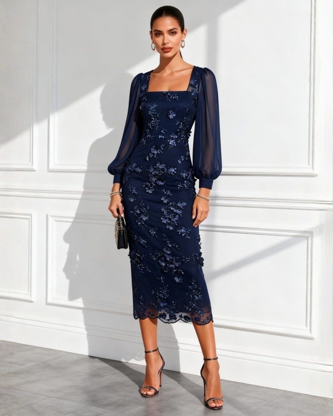 Woman in a navy blue embroidered midi dress with sheer puff sleeves and heels.