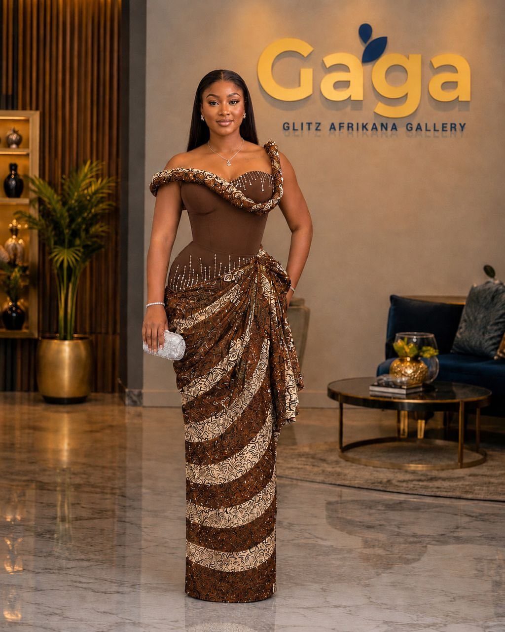Woman wearing a brown and gold sequined off-shoulder gown in a modern gallery.