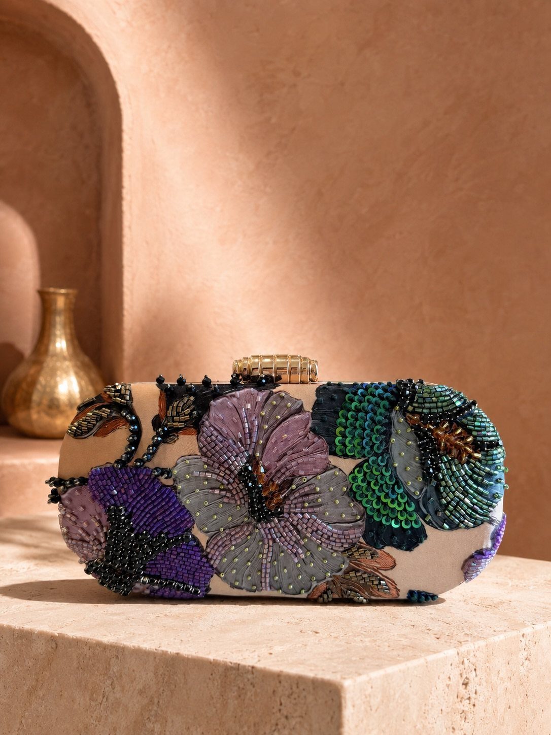 Floral beaded clutch with purple and teal sequins on a stone surface.