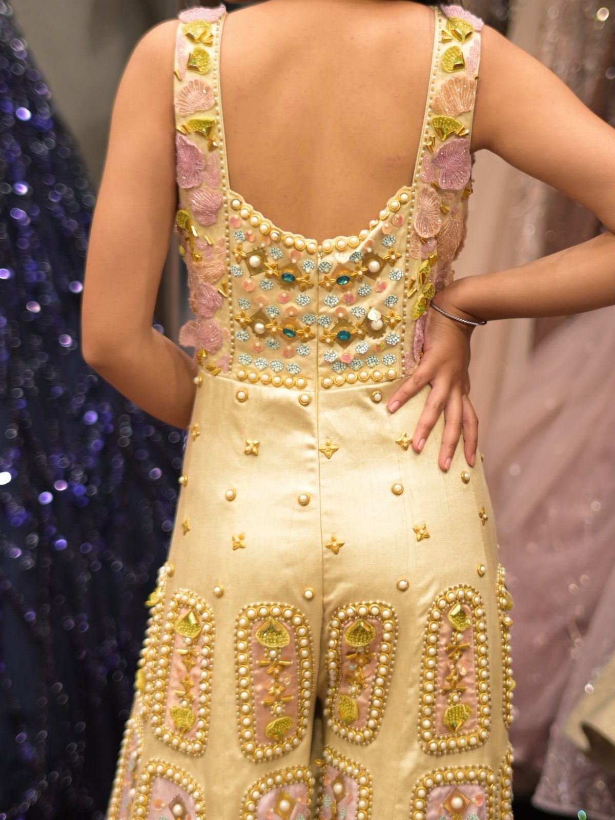 Cream embellished romper with gold embroidery and pearls worn by a person.