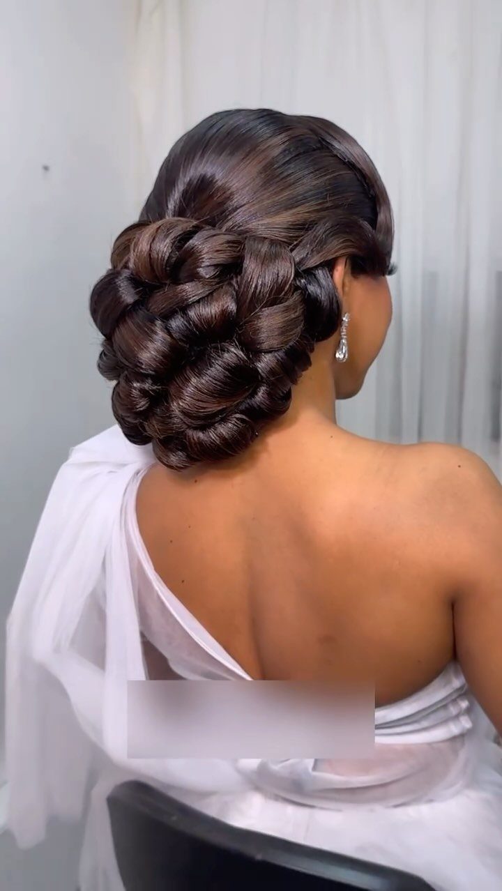 Intricate braided dark brown hair updo on a woman wearing a white dress.