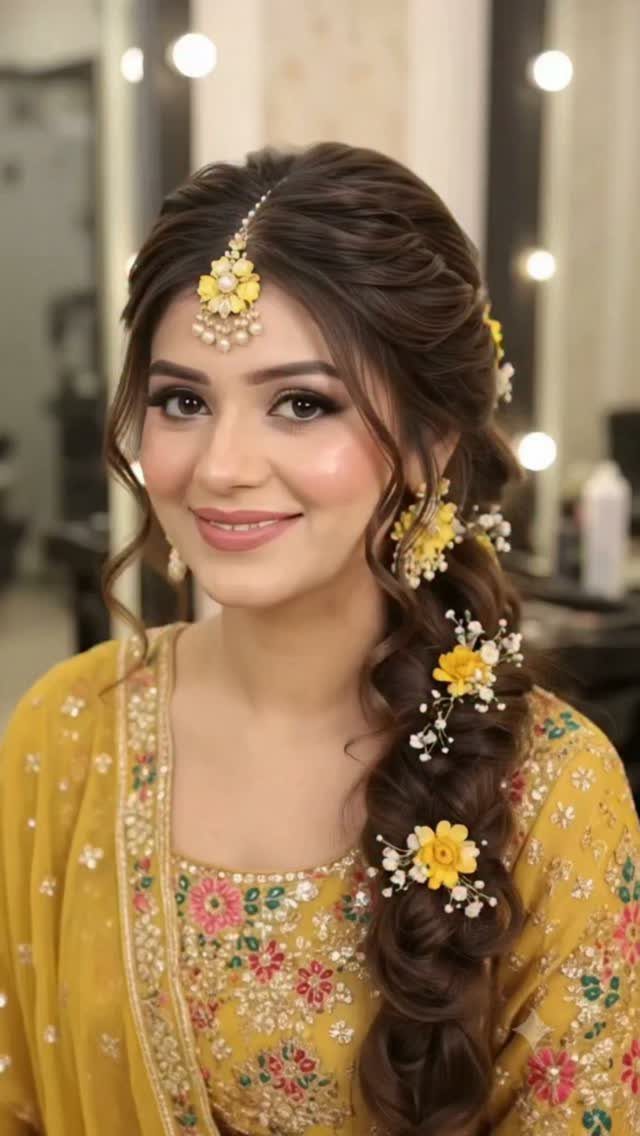 Woman with braided hair and yellow flowers wearing traditional Indian wedding makeup and attire