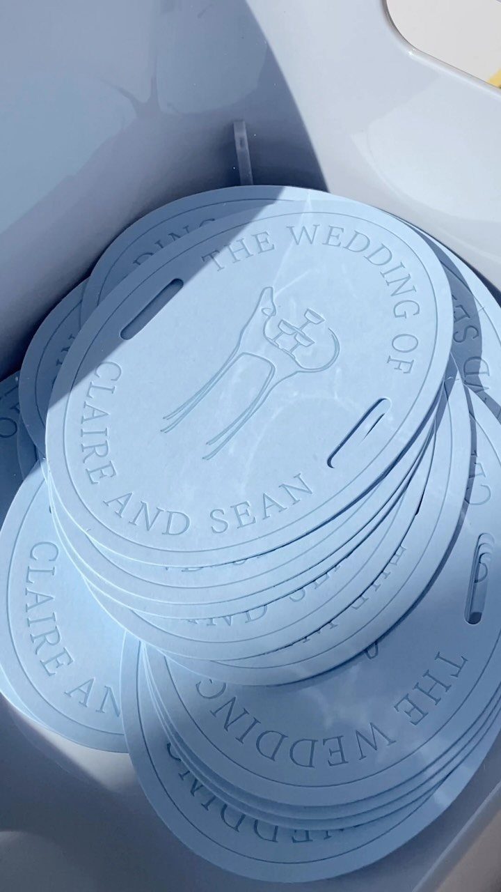 Stack of light blue circular embossed wedding cards for Claire and Sean.