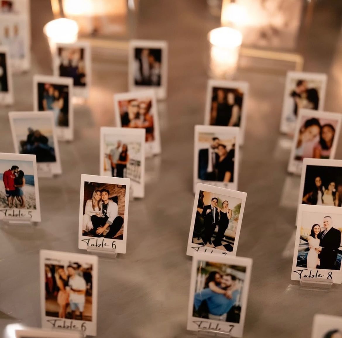 Polaroid photos with table numbers held up by clear acrylic place card holders.