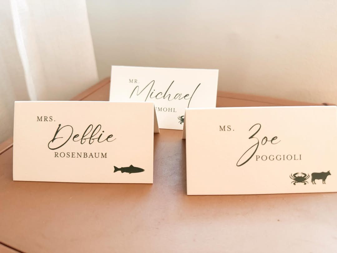 White wedding place cards with guest names and meal choice animal icons.