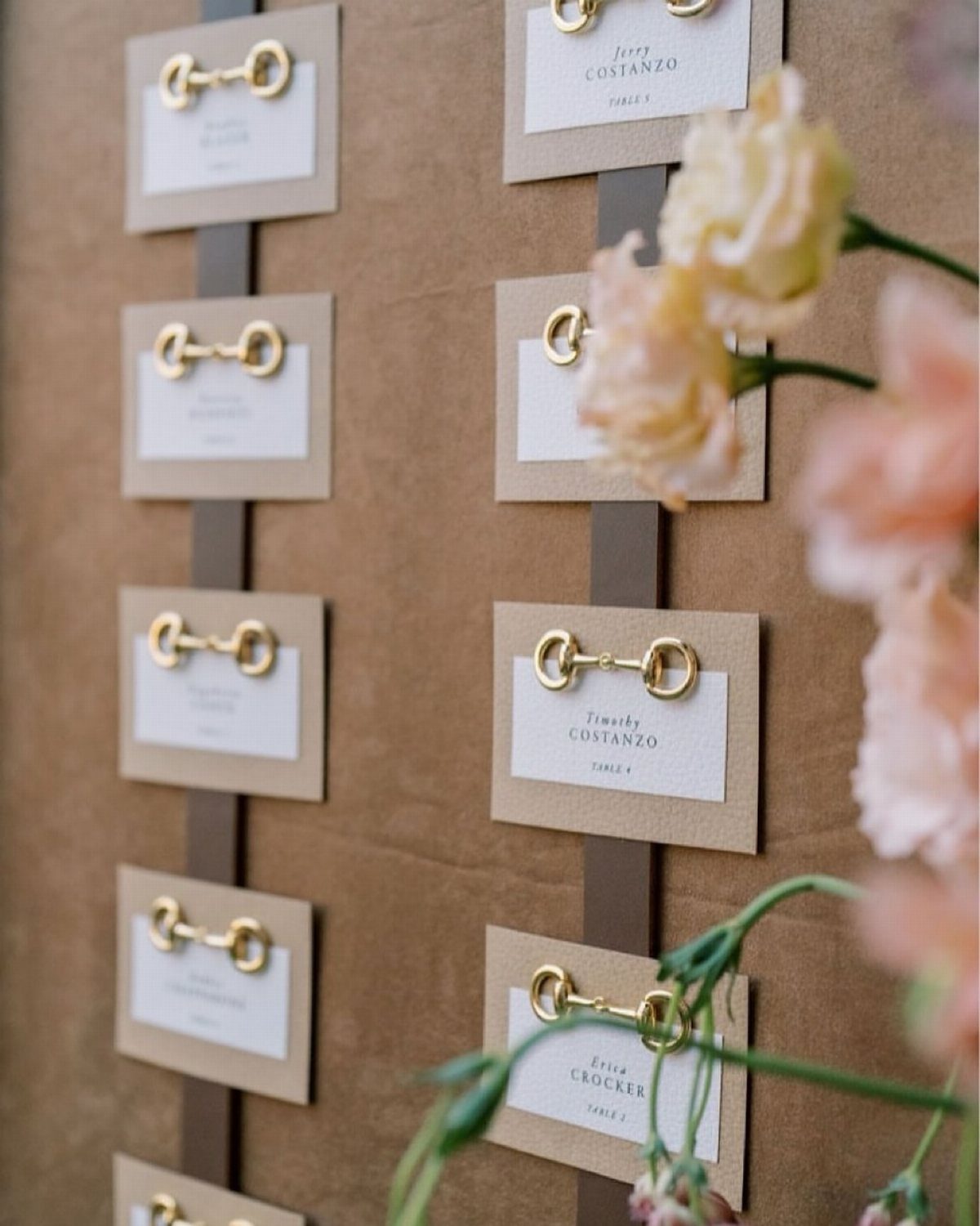 White guest name cards with gold horse-bit accents displayed on a brown board.