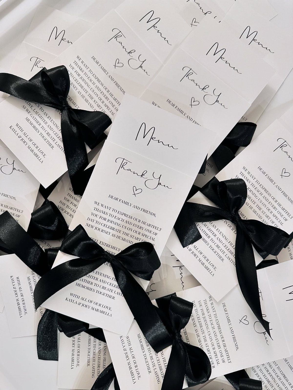 White wedding thank you cards with black cursive text and black satin bows.