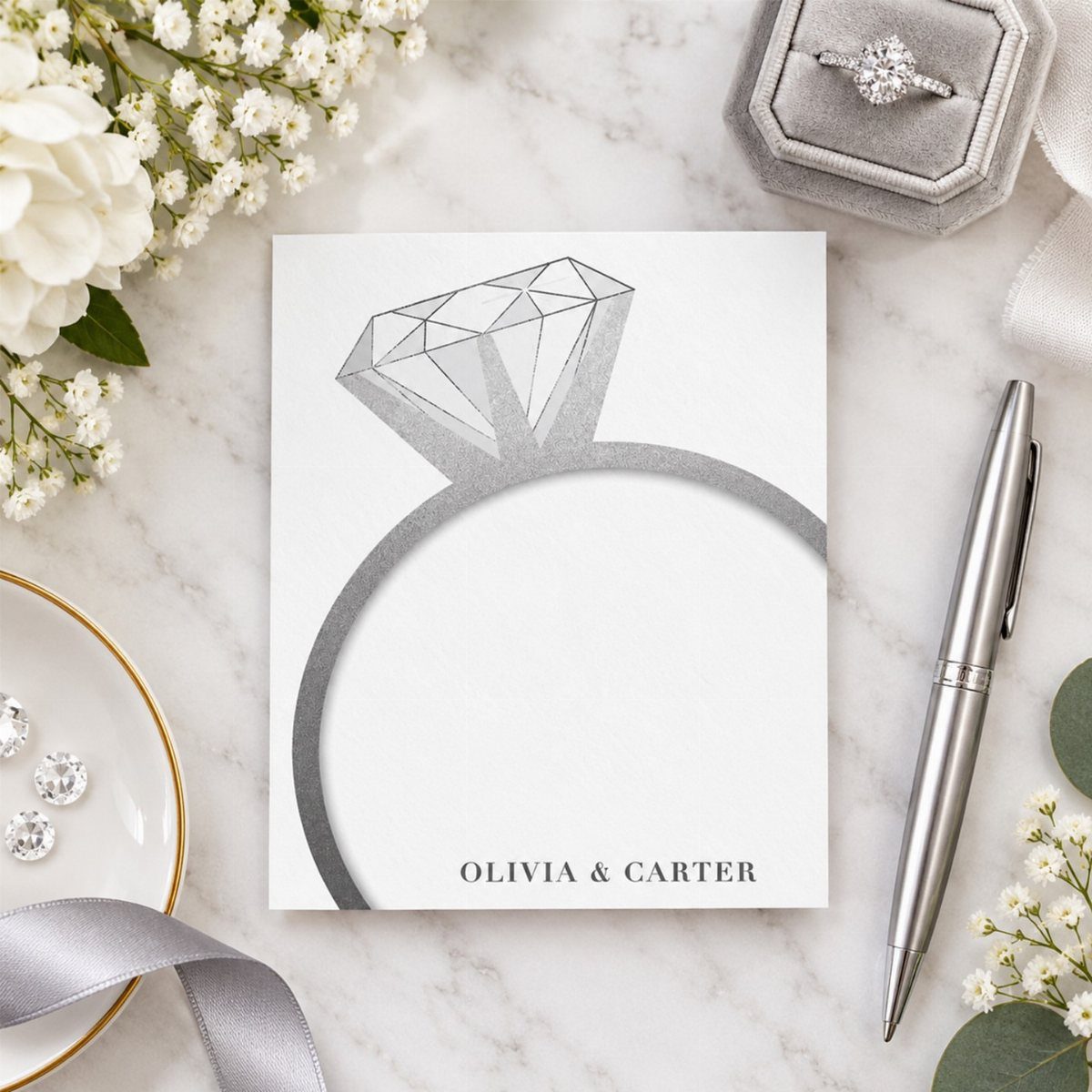White card with diamond ring illustration and names on a marble background.