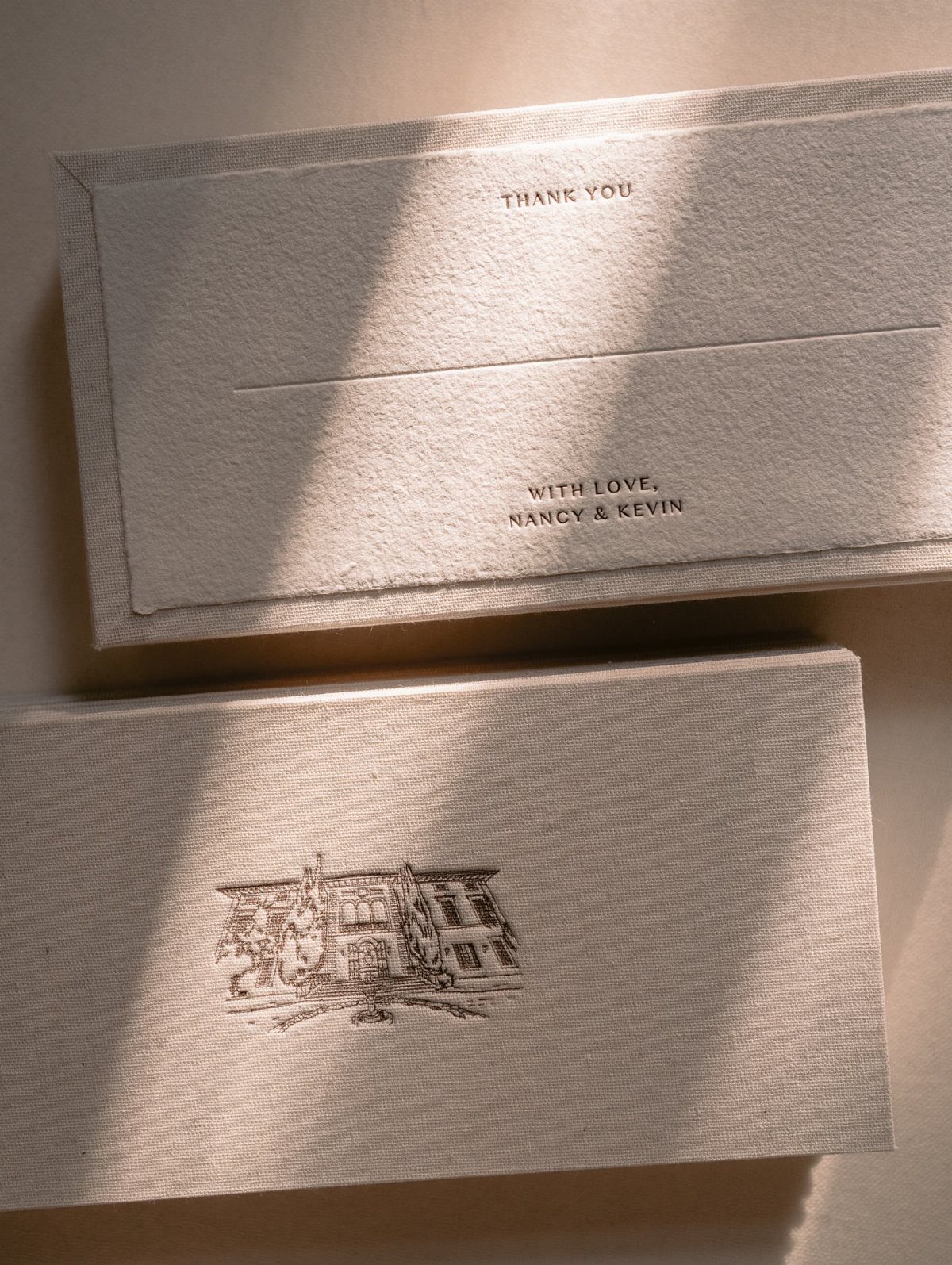 Two cream textured wedding thank you cards, one featuring names of a couple.