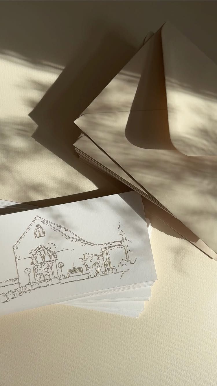White cards with a building sketch and brown kraft envelopes on beige background.