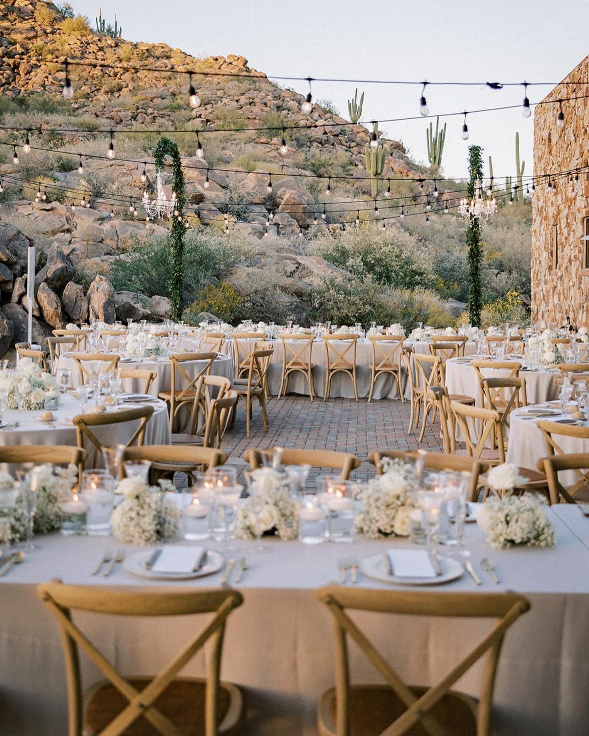 Outdoor wedding reception with white tables and wooden chairs in a rocky Arizona desert