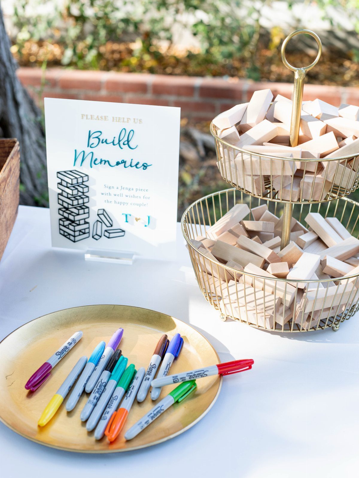 Guest book station with wooden Jenga blocks and colorful markers on a white table.