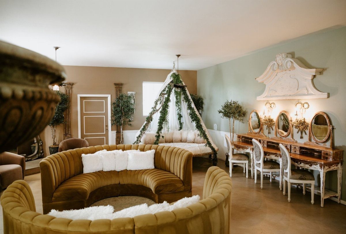 Elegant bridal suite with gold velvet seating, a canopy bed, and a vintage vanity.