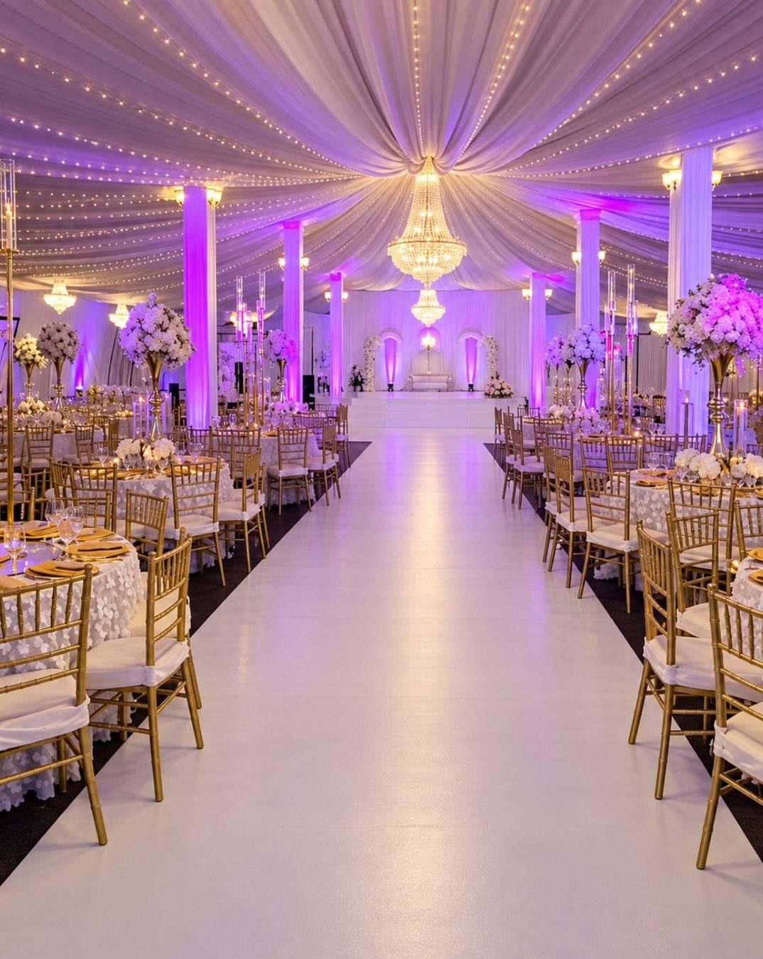 Lavish indoor wedding reception with white draped ceiling, gold chairs, and purple lighting.