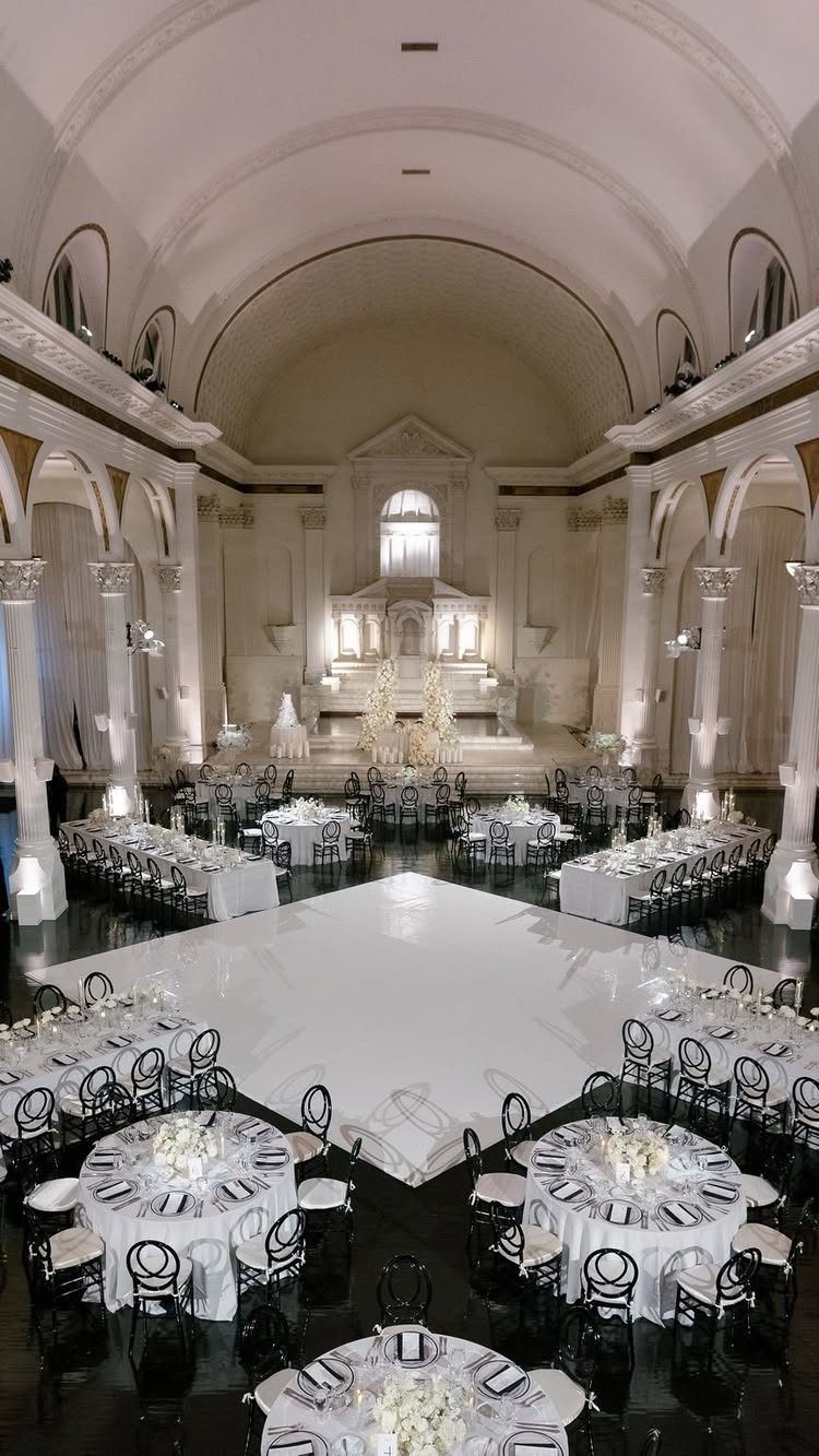 Grand white cathedral interior with a white dance floor and elegant wedding reception tables.