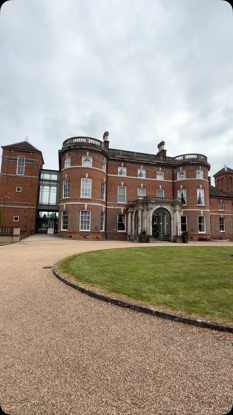 Large red-brick historic mansion with white trim and a curved gravel driveway.