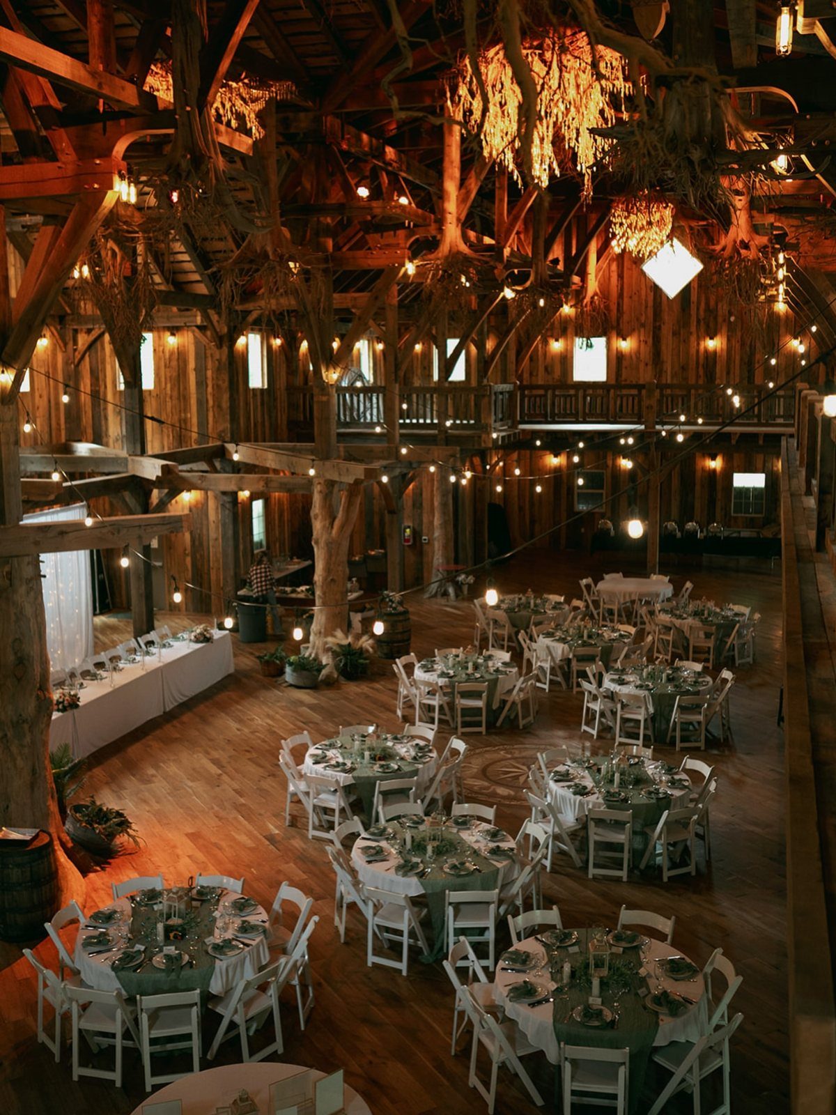 Rustic barn wedding venue interior with exposed wooden beams and elegant dining tables.