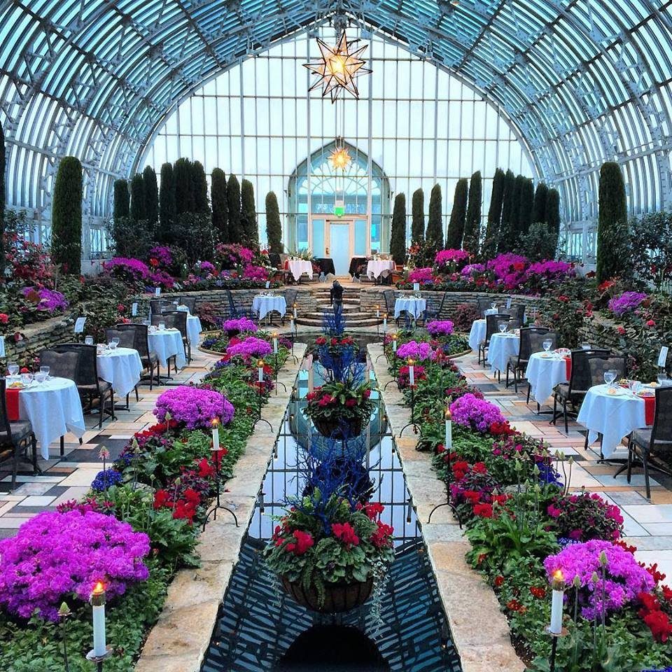 Glass conservatory wedding venue with reflecting pool and colorful flower beds