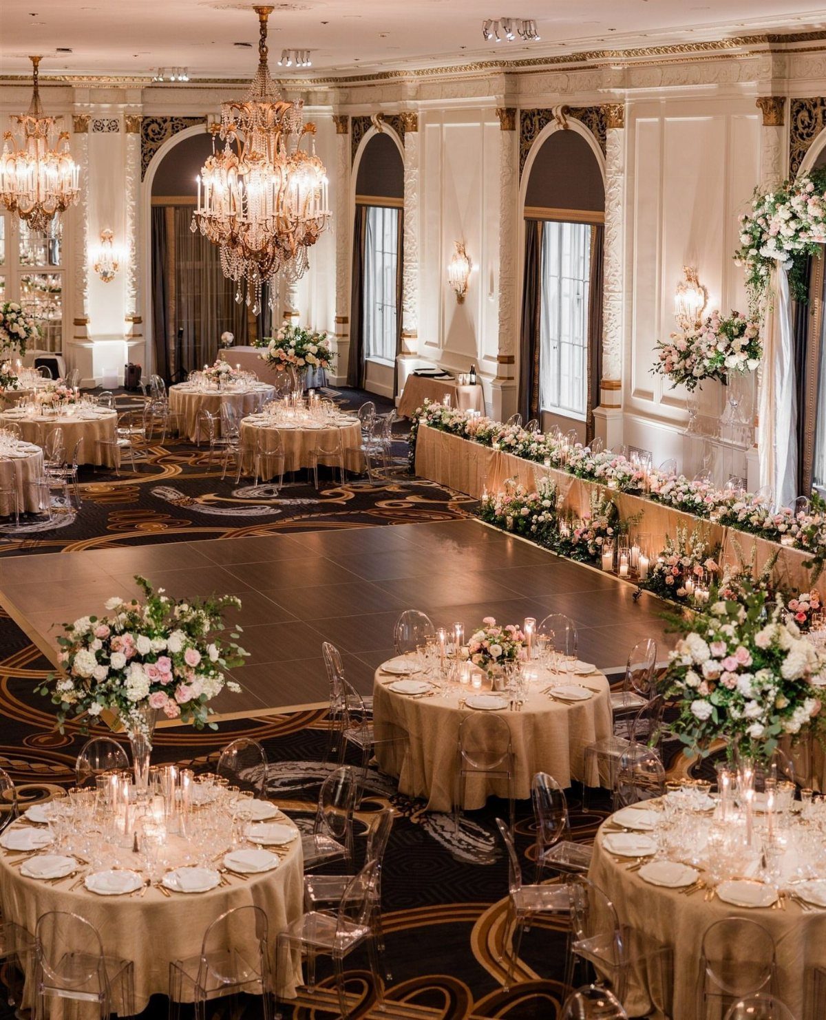 Elegant ballroom wedding reception with gold linens, crystal chandeliers, and floral centerpieces.