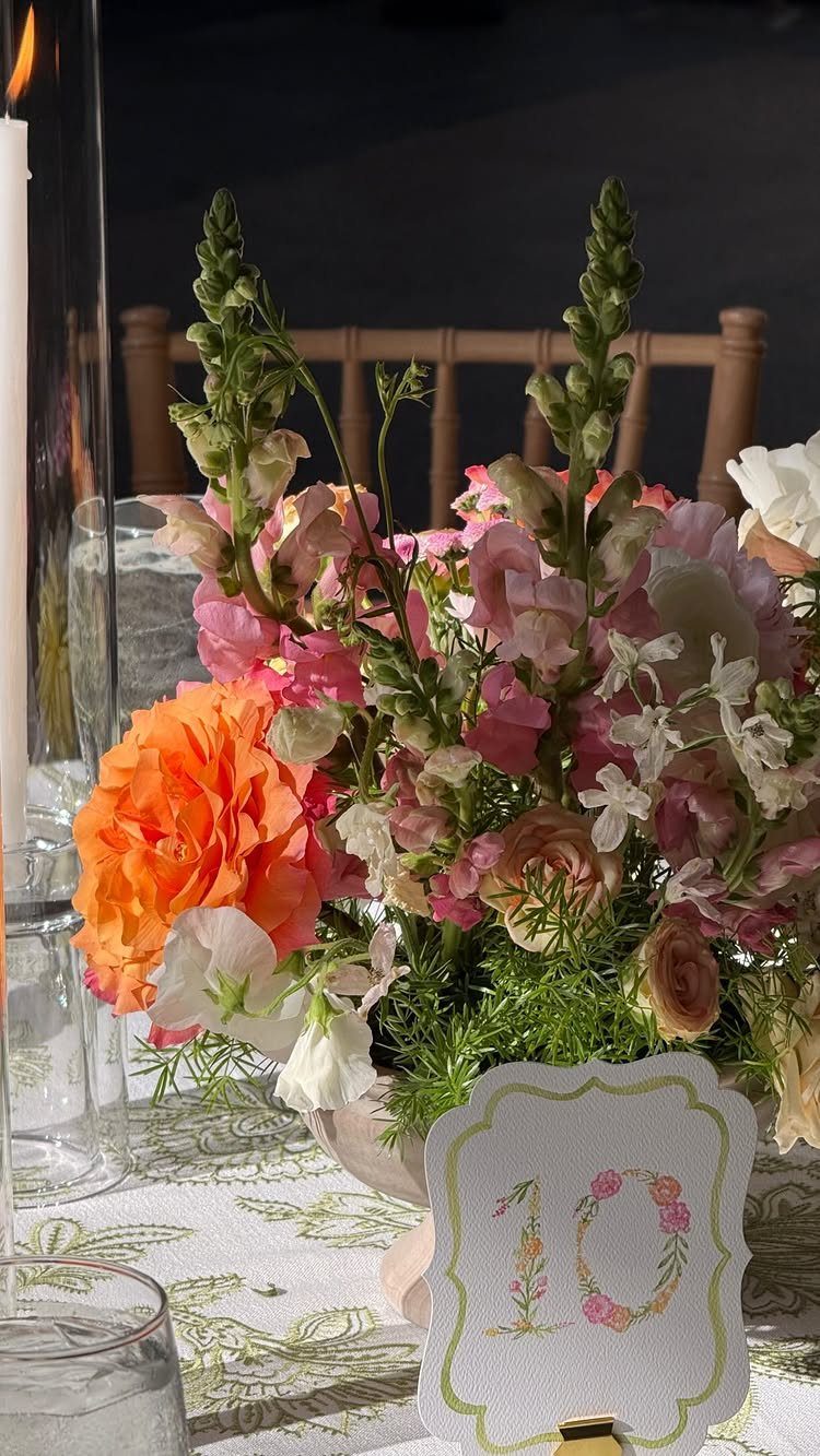 Floral arrangement with a table number 10 on a patterned white tablecloth.