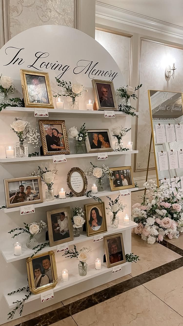 Memory display with framed photos, white flowers, and candles under an In Loving Memory sign.