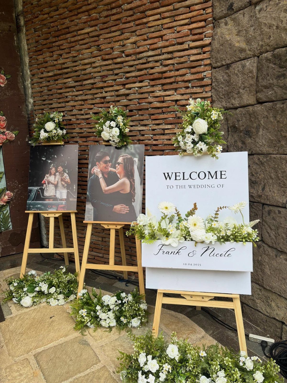 Wedding welcome display with black and white couple photos and a welcome sign on easels.