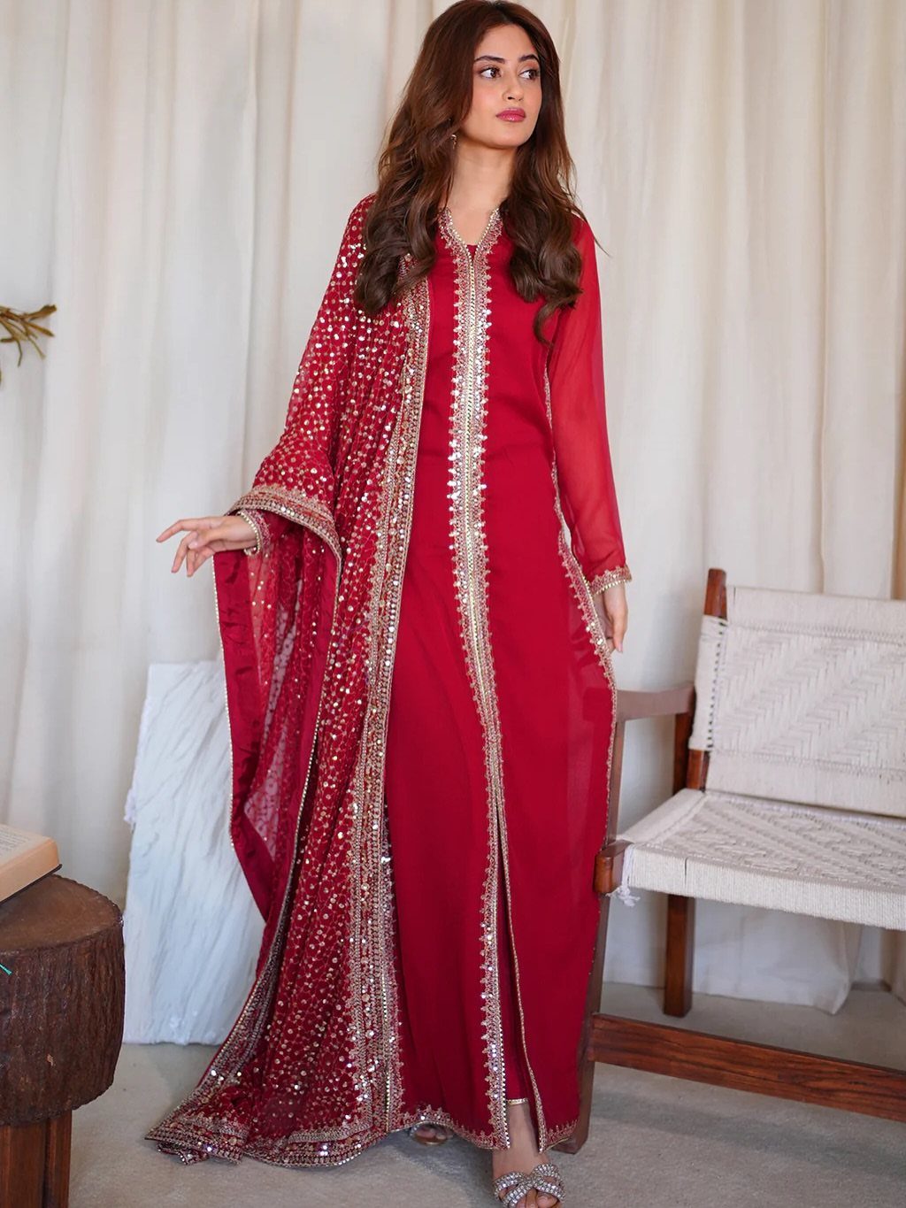 Woman in a red embroidered traditional South Asian dress and matching sequined shawl.